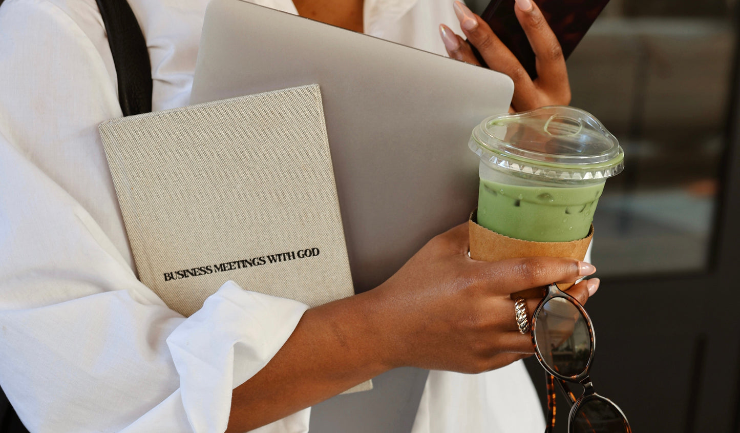 Person holding a coffee cup, sunglasses, and a business meetings with God planner with a blurred background